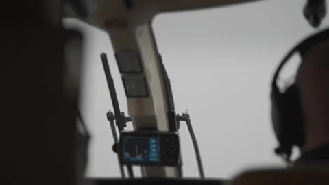 A pilot wearing a headset flying a helicopter in poor visibility. Stock Footage 274053792