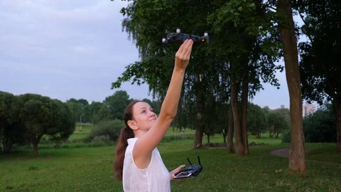 Pilot woman land remote controller drone to hand, evening time in city park Stock Footage 92759480