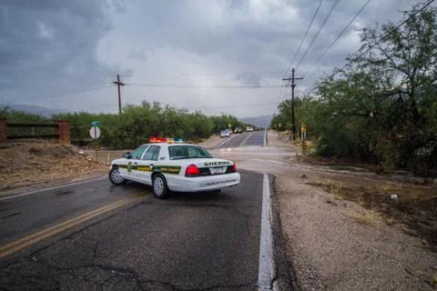 Pima County Sheriff's car blocks flash flooded desert road from traffic Stock Photos