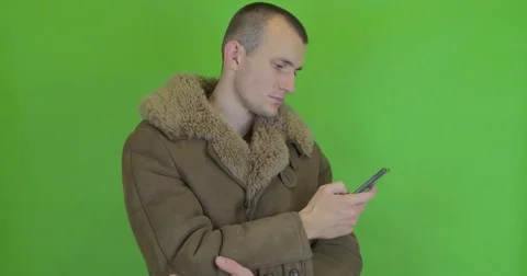 A pimp in a coat flips through the news in the phone Stock Footage 75910401