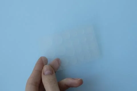 Pimple patch for oily and problematic skin in a woman's hand on a blue backgr Stock Photos