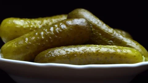 Pimply pickled cucumbers close-up on a white plate on a black background Video stock 172503535