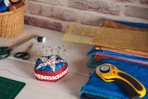Pin cushion stylized elements of American flag, stacks of fabrics, quilting.. 스톡 사진