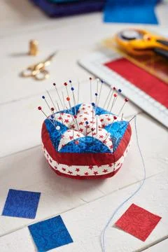Pin cushion stylized elements of American flag, stacks of fabrics, quilting.. Stock Photos