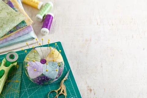Pincushion, stack of fabrics, sewing and quilting accessories Fotos Stock