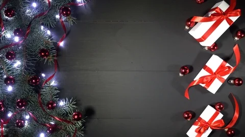 Pine branches adorned with baubles, shimmering lights and gifts with red ribbon Stock Footage 99064877