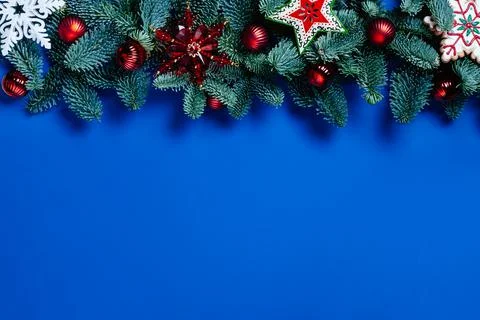 Pine branches, bauble, white and red snowflakes on blue background. Stock Photos