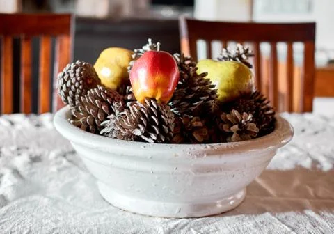 Pine cones artificial apple and pear in white pottery on dining table Stock Photos