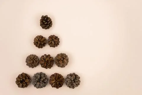 Pine cones stacked in the shape of a Christmas tree on a beige background Stockfoto's