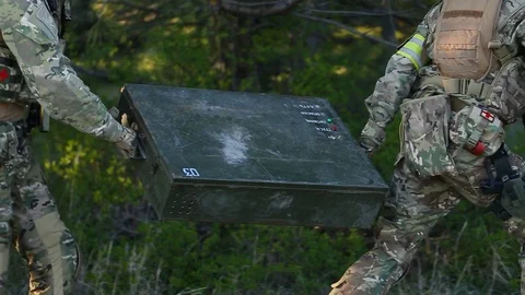 In pine forest. The equipped soldiers captured the enemy's iron box. airsoft Stock Footage 127857648