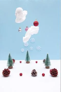 Pine forest in the snow with clouds from which New Year's decorations fall. C Stock Photos