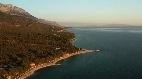 Pine forest surrounds Oseka pebble beach at sunset in Baska Voda Croatia Stock Footage 345726538