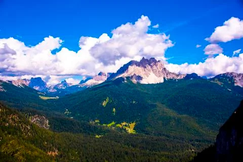 Pine forests and pink dolomites among white clouds Stock Photos