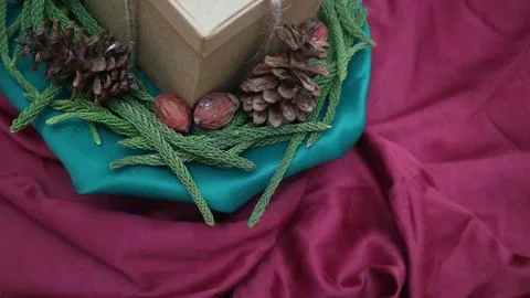 Pine leaves, dried pine, and gift box with red background. Concept of Christmas Stock-Fotos