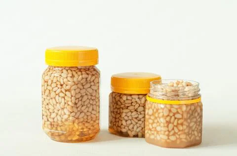 Pine nut with honey In a transparent jar with a yellow lid. Nearby are jars o Stock Photos
