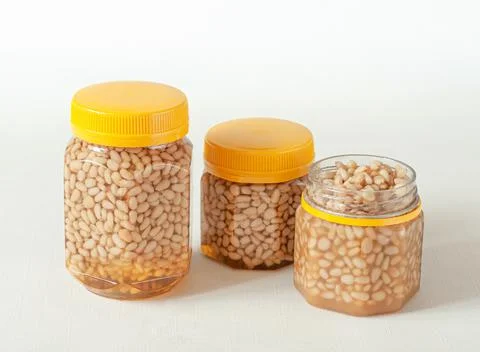 Pine nut with honey In a transparent jar with a yellow lid. Nearby are jars o Stock Photos