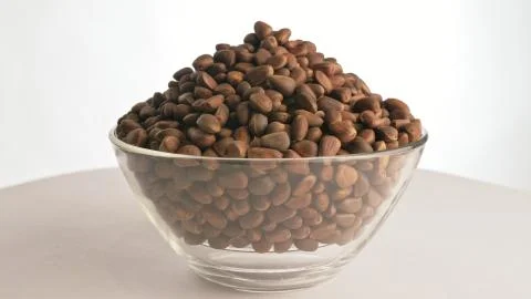 Pine nut rotate are on a table in a plate. Snack in transparent dish on an Stock Photos