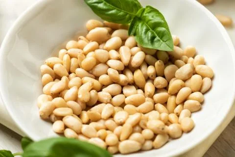 Pine nuts and fresh basil in a small bowl. Ingredients for a pesto sauce Stock Photos