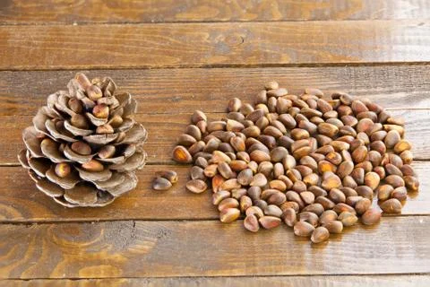 Pine nuts and pine cone on wooden table Stock Photos