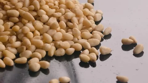 Pine nuts are poured onto the frying surface Stock Footage 302213937