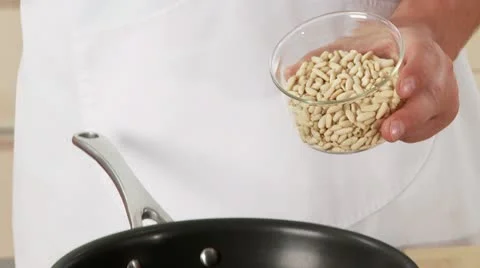 Pine nuts being added to a non-stick pan and roasted 스톡 동영상 24636966