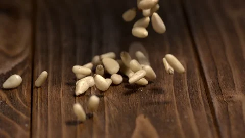 Pine nuts fall on wooden table during cooking preparations in the kitchen Stock Footage 323147931