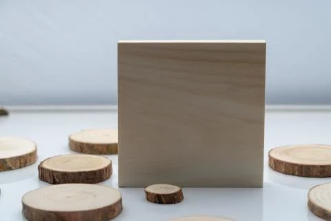 Pine tree cross-sections with annual rings and wooden square on white surface Stock Photos