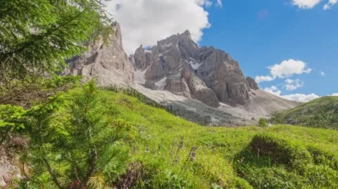 Pine trees blow in the wind as clouds roll through the blue sky over a mountain. Stock Footage 68312091
