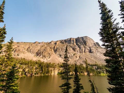 Pine trees in the foreground of an alpine lake in the Rocky Mountains with a  Foto stock