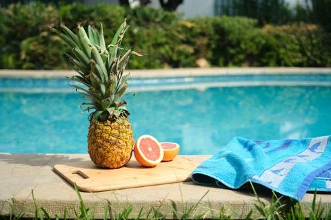 Pineapple and grapefruit on the edge of the pool Stock Photos