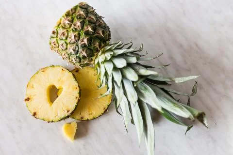 Pineapple and its slice with a heart shaped cut out lying on white background Stock Photos