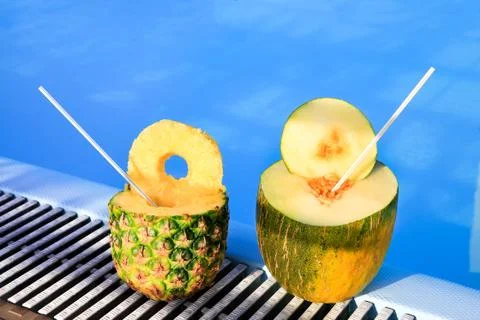 Pineapple and melon fruit with straws at swimming pool Stock Photos