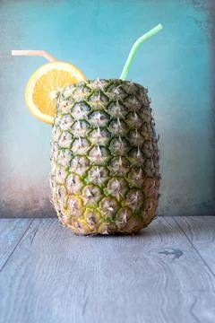 Pineapple and oranges with straws close-up on wood on grungy blue  background Stock Photos