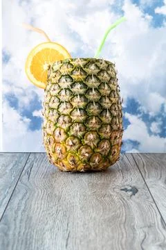 Pineapple and oranges with straws close-up on wood on sky  background Stock Photos