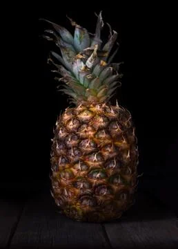 Pineapple on black isolated background on old rustic desk. Stock Photos