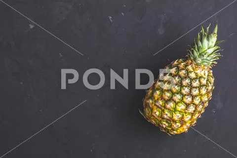 Pineapple on black stone concrete textured surface Stock Photos
