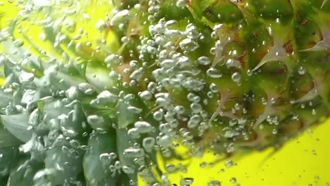 Pineapple with bubbles on yellow background copy space slow motion falling water Stock Footage 156404556