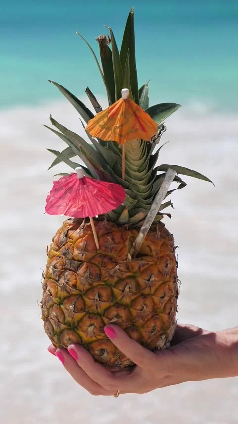 Pineapple cocktail in hand with beach background. Travel destinations  Stock Footage 314430395