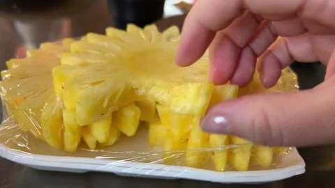 Pineapple dots cut out in floral pattern on plastic plate hand breaks off food 動画素材 306276134