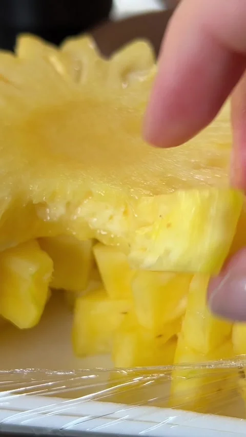 Pineapple dots cut out in floral pattern on plastic plate hand breaks off food 動画素材 306681940