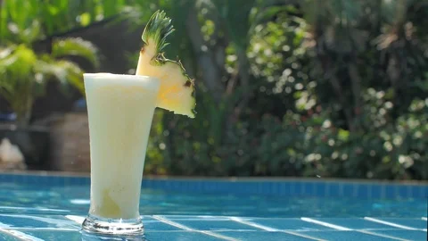 Pineapple freshly juice with slice of fruit on blue pool background at sunny day 動画素材 102179831