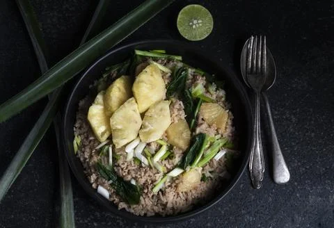 Pineapple fried rice has minced pork and vegetable in plate on stone table. Stock Photos