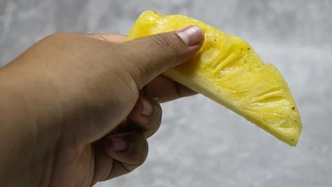 Pineapple fruit slice held by hand on gray background with concrete texture Stock Photos