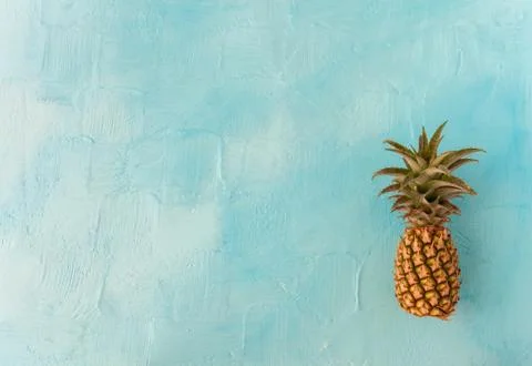 Pineapple with green stem, on blue background. Large space for text. flat layout Stock Photos