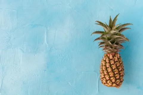 Pineapple with green stem, on blue background. Large space for text. flat layout Foto stock