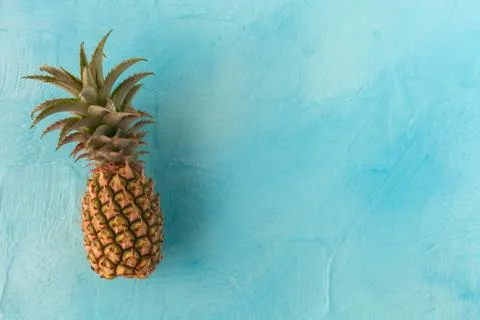 Pineapple with green stem, on blue background. Large space for text. flat layout Stock Photos