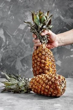 Pineapple in hands on the cement background Stock Photos