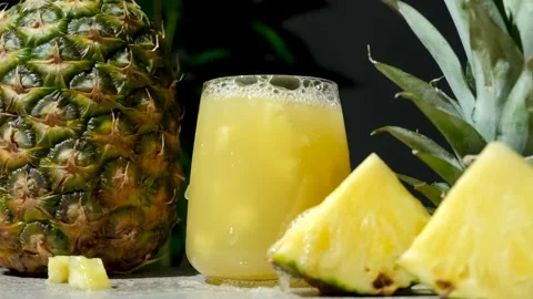 Pineapple juice splash, slow motion. Pieces of fresh pineapple fall into a glass Stock Footage 296372294