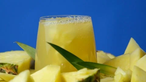 Pineapple juice splash, slow motion. Pieces of fresh pineapple fall into a glass Stock Footage 296374057
