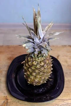 Pineapple on the kitchen table in a plate Stock Photos